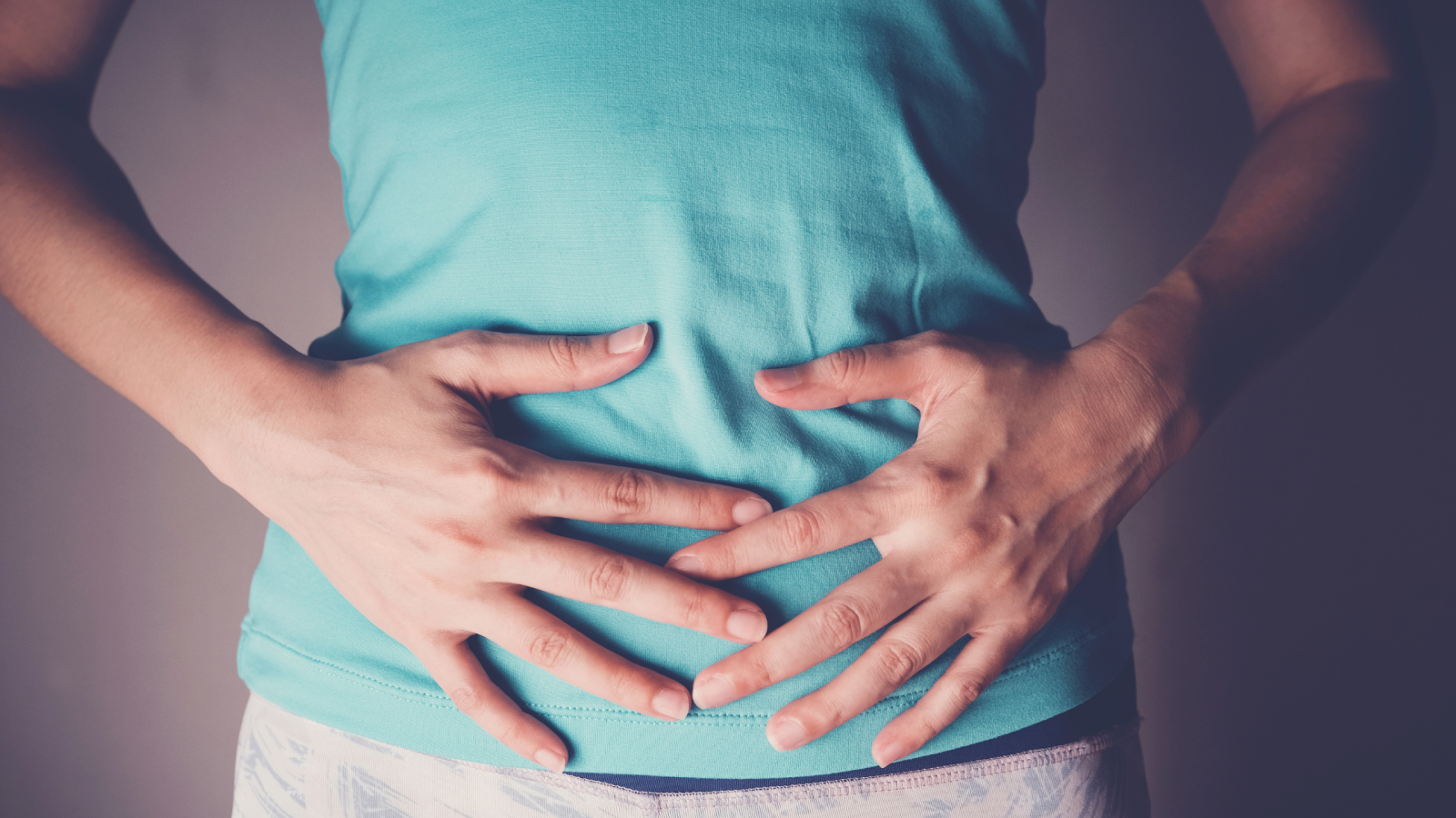 Hands wrapped around the stomach area, suggestive of thought on IVF after a tubal ligation procedure.