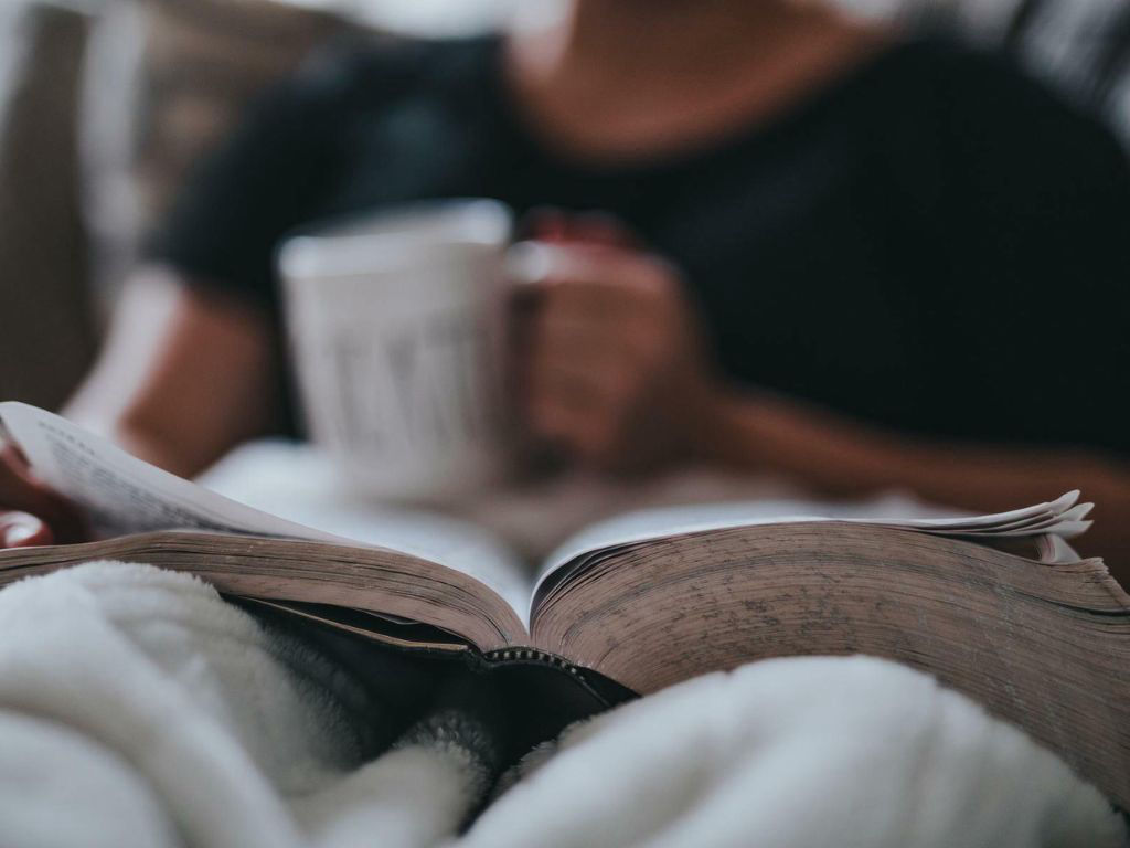 Reading a book and holding a mug